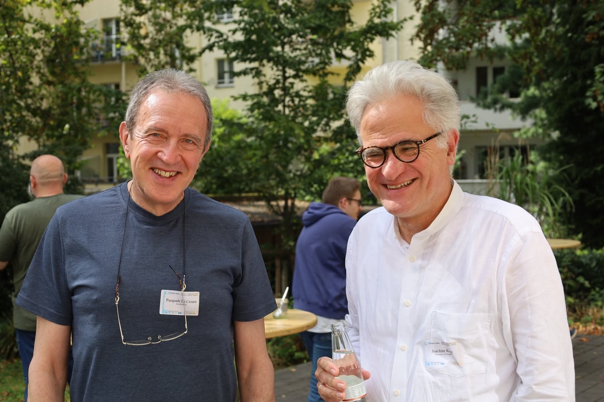 Pasquale Di Cesare and Joachim Krug smiling in the courtyard.
